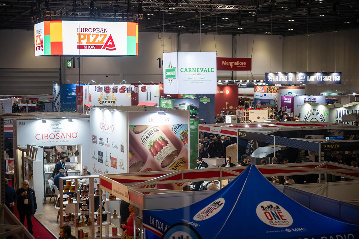 A large hall with exhibitor stands and visitors.